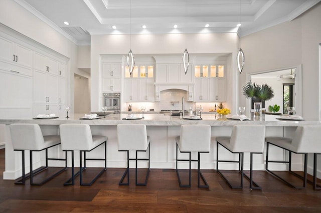 81 S River Rd, Stuart, FL 34996 - kitchen featuring tasteful backsplash, stainless steel oven, white cabinets, and a kitchen breakfast bar
