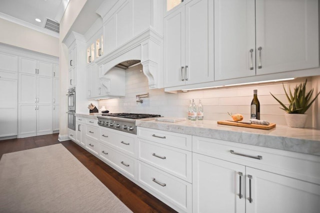 81 S River Rd, Stuart, FL 34996 - kitchen with glass insert cabinets, white cabinetry, light stone countertops, visible vents, and stainless steel appliances
