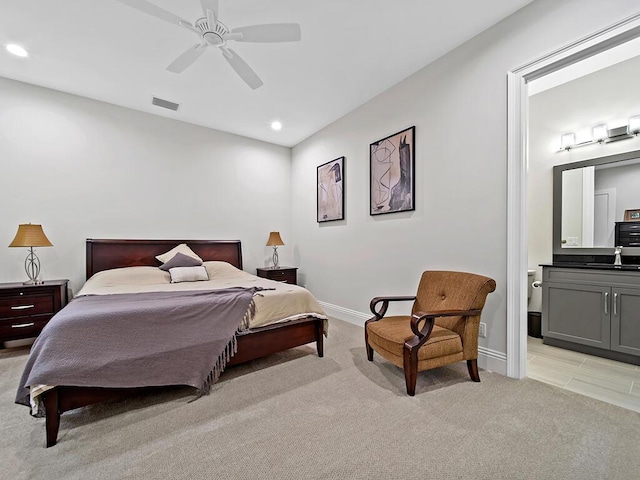 bedroom featuring ensuite bathroom, sink, light carpet, and ceiling fan