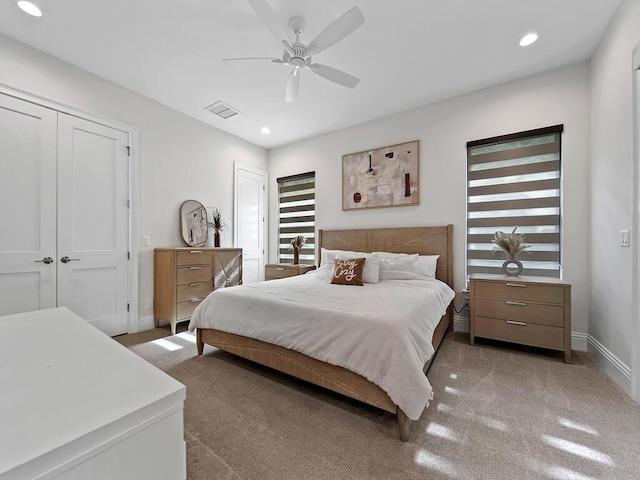 carpeted bedroom featuring multiple closets and ceiling fan