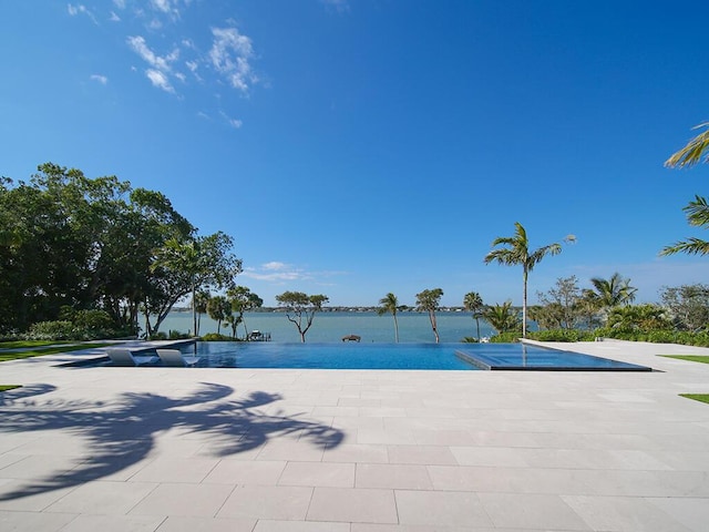 view of pool with a water view and a patio area