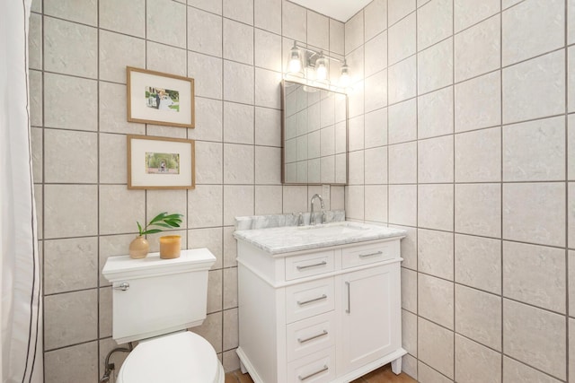 bathroom featuring vanity, toilet, and tile walls