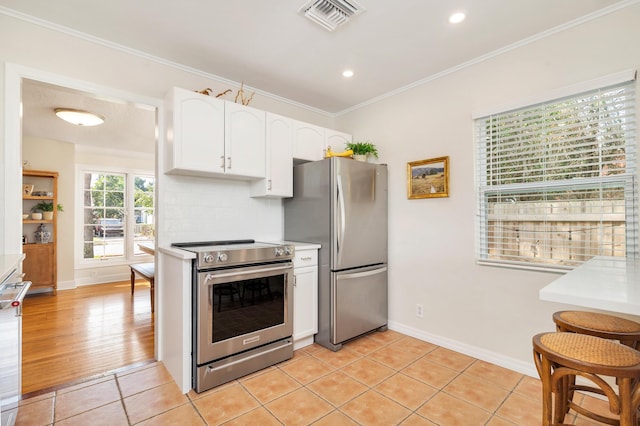 kitchen with light tile patterned floors, crown molding, stainless steel appliances, white cabinets, and decorative backsplash