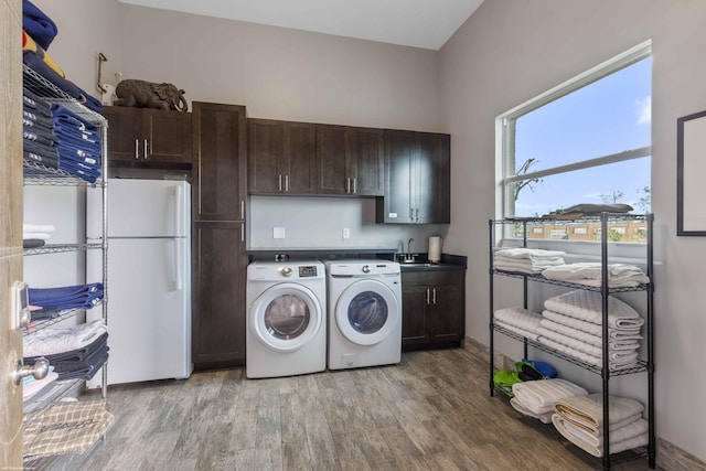 laundry room with sink, hardwood / wood-style flooring, washing machine and dryer, and cabinets