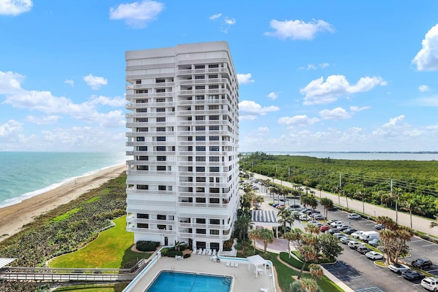 exterior space featuring a view of the beach, a community pool, and a water view