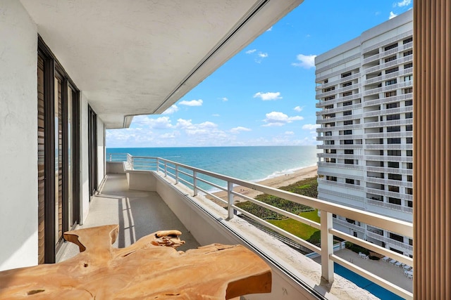 balcony with a water view and a view of the beach