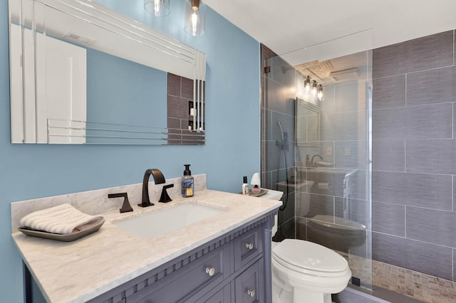 bathroom featuring a shower with door, vanity, and toilet