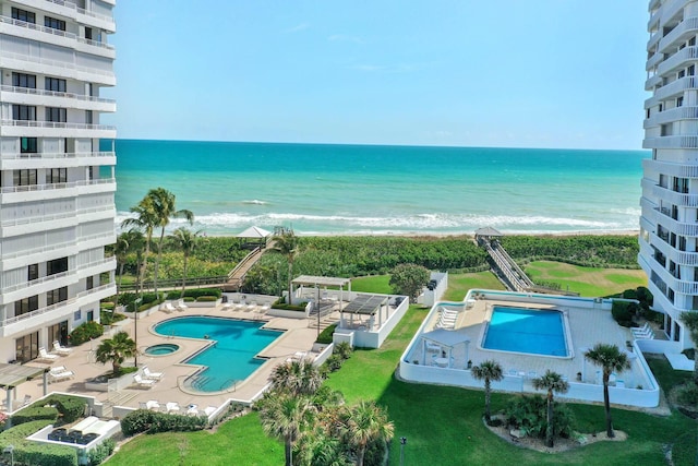 view of pool with a water view, a beach view, and a patio area