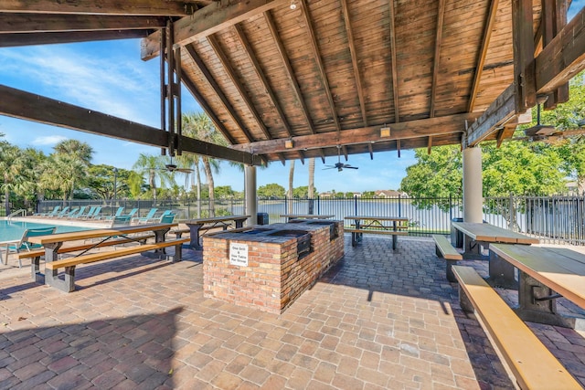 view of patio / terrace featuring a bar, ceiling fan, a community pool, and area for grilling