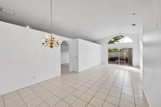 empty room with vaulted ceiling, a chandelier, a textured ceiling, and light tile patterned flooring