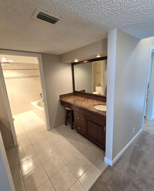 bathroom featuring vanity, tile patterned flooring, a bathtub, and a textured ceiling