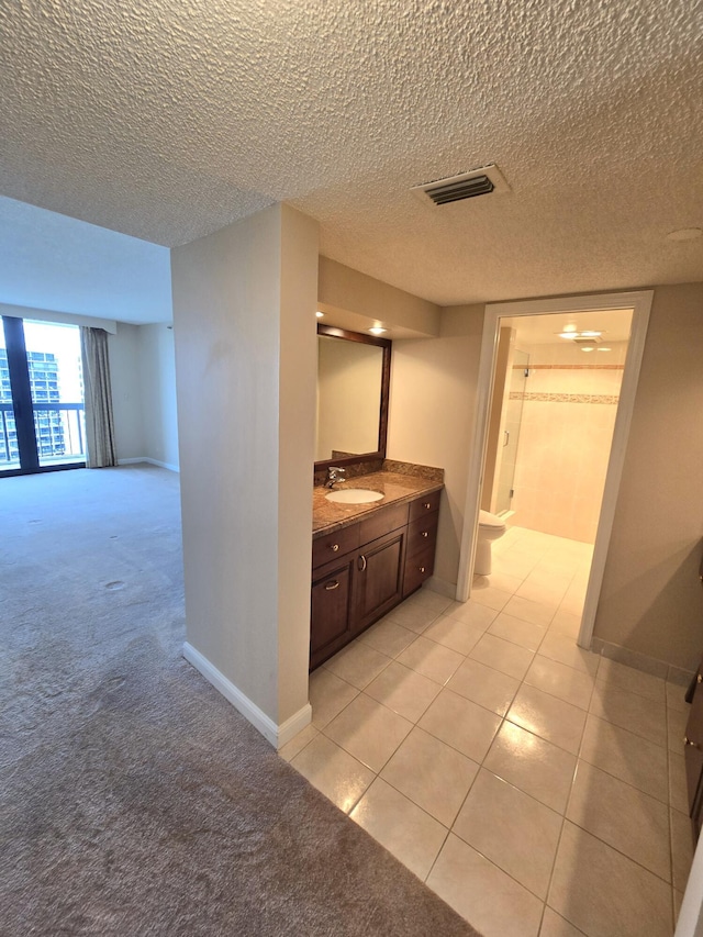 bathroom with tile patterned flooring, vanity, a textured ceiling, and toilet