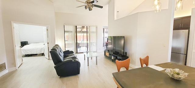 living room with ceiling fan, high vaulted ceiling, and light wood-type flooring