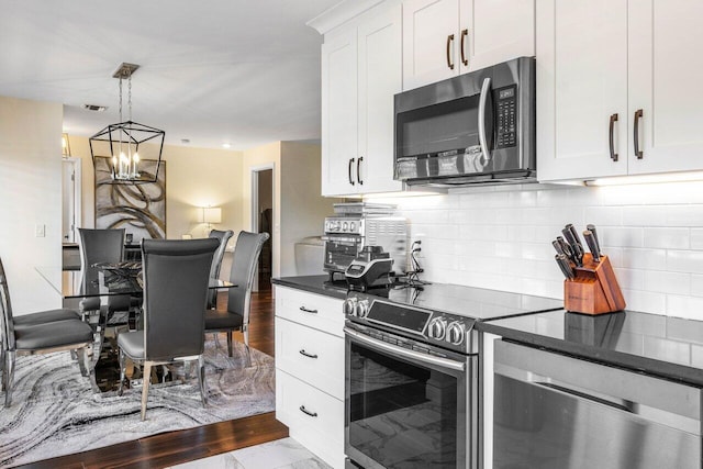 kitchen with pendant lighting, decorative backsplash, stainless steel appliances, and white cabinets