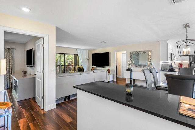 kitchen featuring dark wood-type flooring, decorative light fixtures, a chandelier, and white cabinets