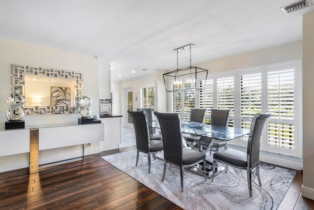 dining room with a notable chandelier, decorative columns, and dark hardwood / wood-style floors