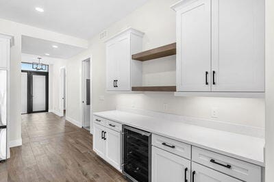 kitchen featuring wine cooler, dark hardwood / wood-style flooring, white cabinets, and an inviting chandelier