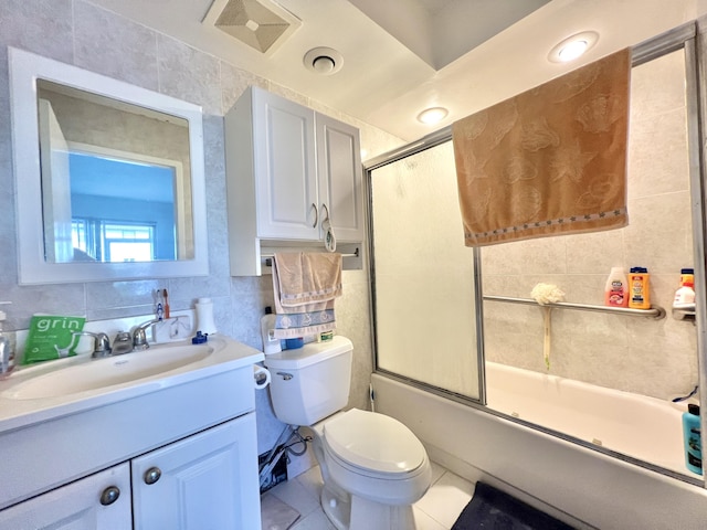 full bathroom with tile walls, shower / bath combination with glass door, vanity, toilet, and tile patterned floors