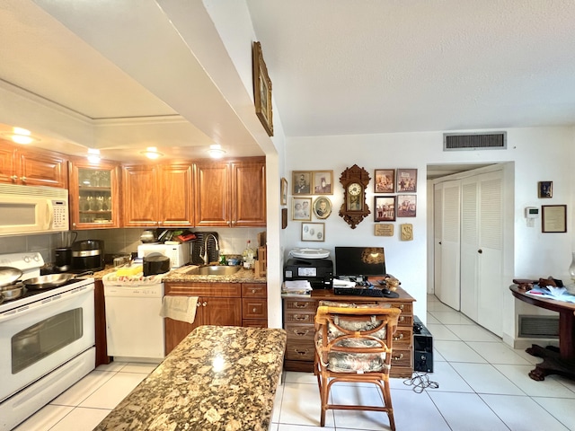 kitchen with sink, white appliances, light tile patterned floors, backsplash, and light stone countertops