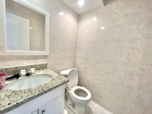 bathroom with vanity, toilet, and tile walls