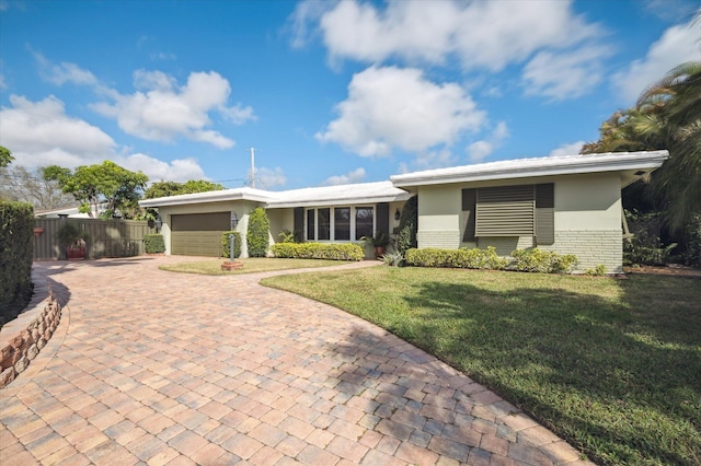 ranch-style house featuring a garage and a front lawn