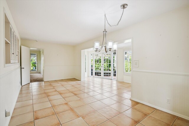 unfurnished room with light tile patterned floors and an inviting chandelier