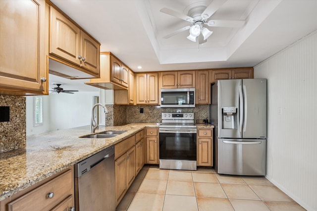 kitchen featuring light tile patterned flooring, sink, light stone counters, a tray ceiling, and stainless steel appliances