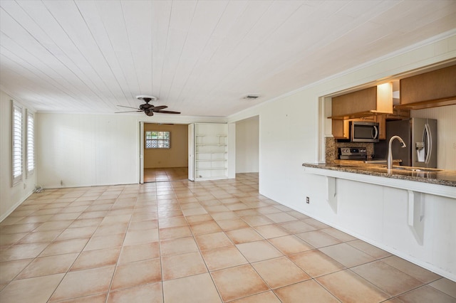 unfurnished living room featuring light tile patterned floors, crown molding, sink, and ceiling fan