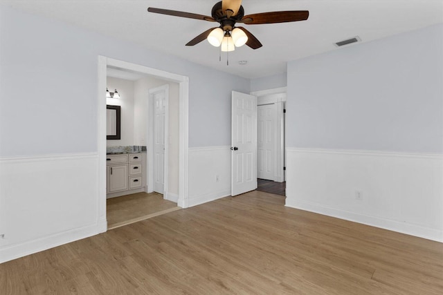 unfurnished bedroom with light hardwood / wood-style floors, ceiling fan, and ensuite bathroom