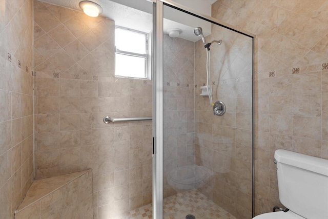 bathroom with a tile shower and toilet