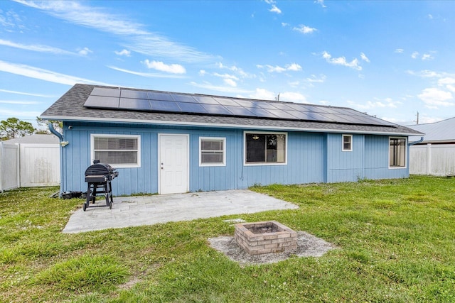 back of property featuring a patio, solar panels, a fire pit, and a lawn