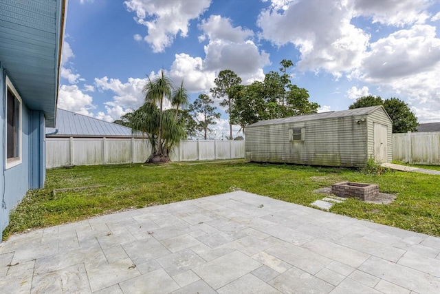 view of yard with a storage unit, an outdoor fire pit, and a patio area