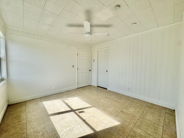 tiled spare room featuring ceiling fan