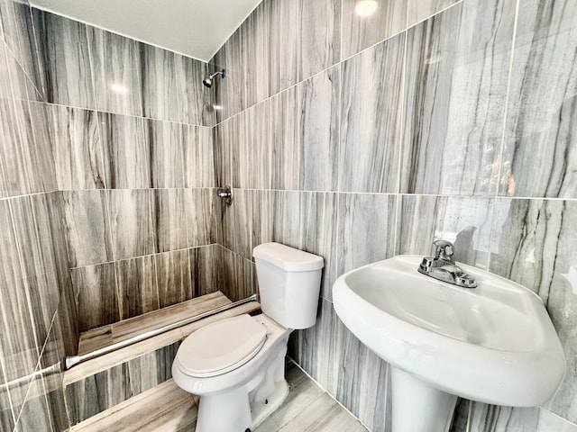 bathroom featuring tiled shower, sink, tile walls, and toilet