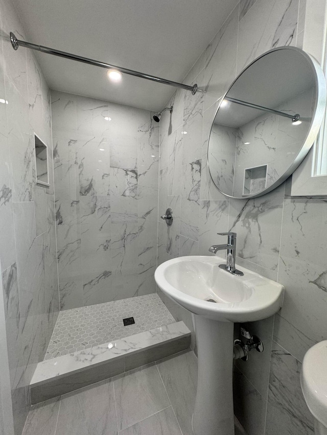 bathroom with toilet, sink, and a tile shower