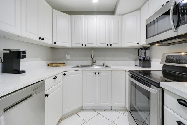 kitchen featuring sink, stainless steel refrigerator, range, white cabinetry, and kitchen peninsula