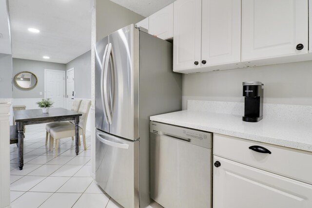 kitchen with white cabinetry, light tile patterned floors, light stone counters, and stainless steel appliances