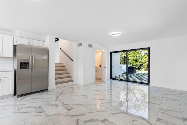 kitchen with tasteful backsplash, stainless steel refrigerator with ice dispenser, and white cabinets