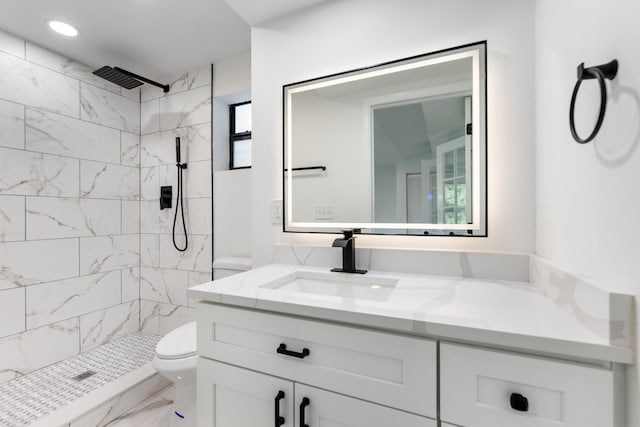 bathroom featuring vanity, toilet, and a tile shower