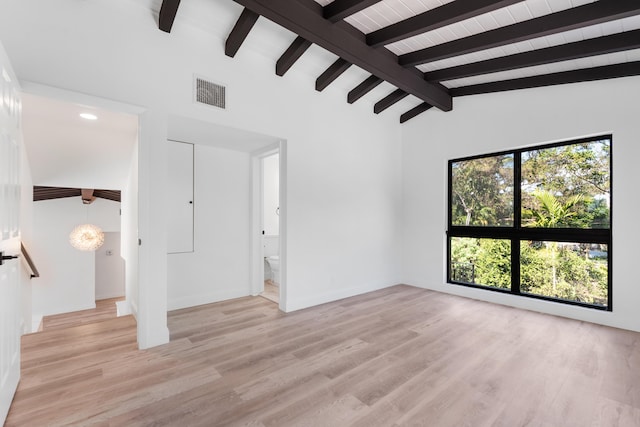 spare room featuring lofted ceiling with beams and light wood-type flooring