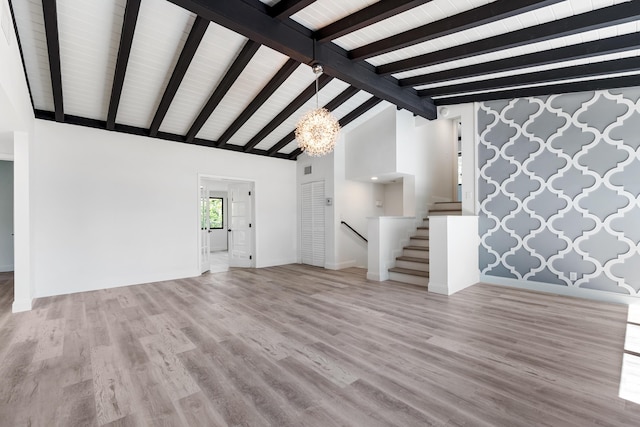 unfurnished living room with vaulted ceiling with beams, an inviting chandelier, and light wood-type flooring