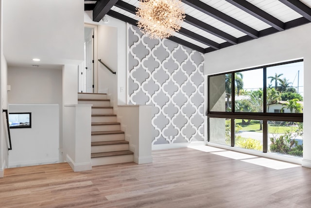 unfurnished living room with an inviting chandelier, beam ceiling, high vaulted ceiling, and light wood-type flooring