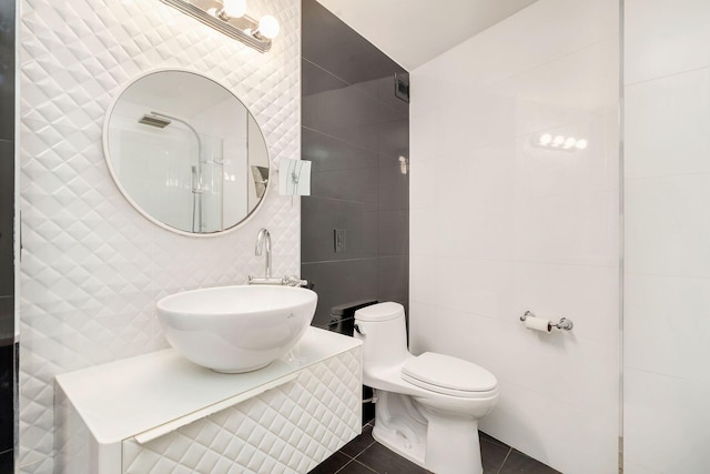 bathroom featuring tile patterned floors, toilet, sink, and tile walls