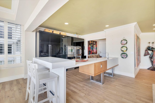 kitchen featuring crown molding, a breakfast bar, light hardwood / wood-style floors, and kitchen peninsula