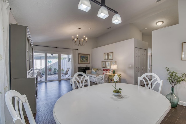 dining area featuring vaulted ceiling, dark wood-type flooring, and a notable chandelier