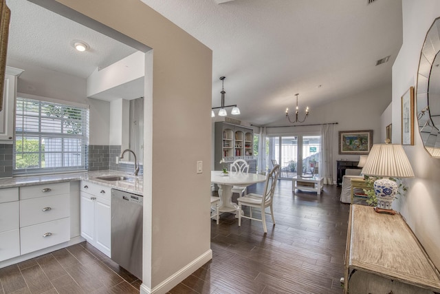 kitchen featuring a sink, dishwasher, decorative backsplash, healthy amount of natural light, and vaulted ceiling