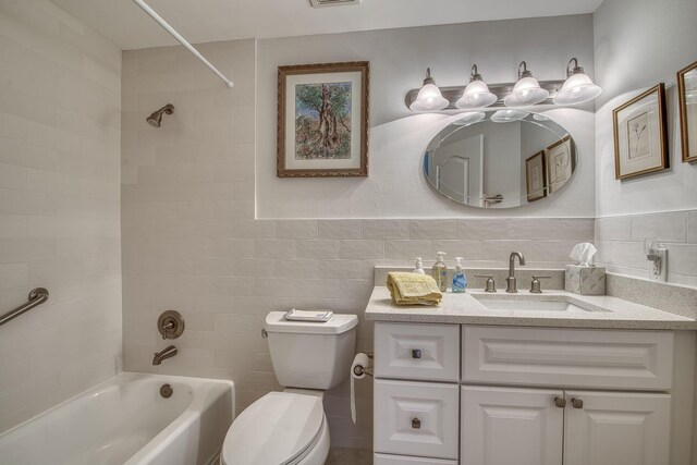 full bathroom with tile walls, toilet, tub / shower combination, and vanity