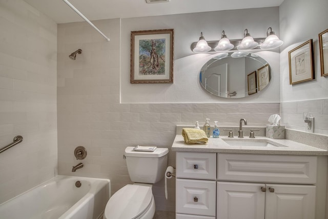 full bathroom with tile walls, vanity, toilet, and tiled shower / bath