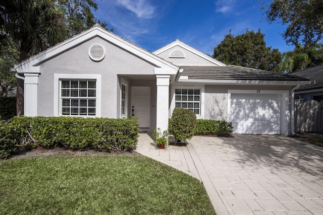 ranch-style house featuring an attached garage, stucco siding, driveway, and a front lawn