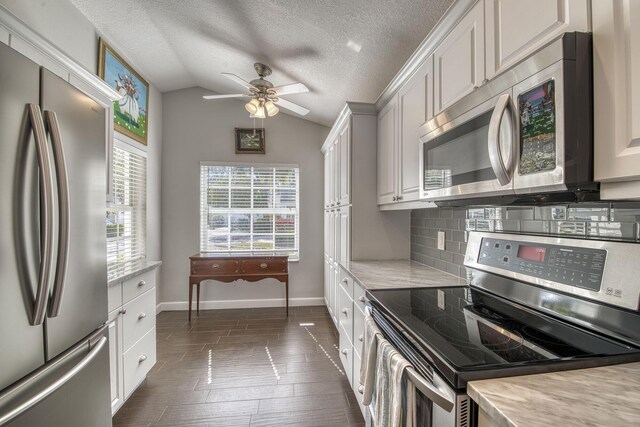 kitchen with stainless steel appliances, tasteful backsplash, lofted ceiling, ceiling fan, and baseboards
